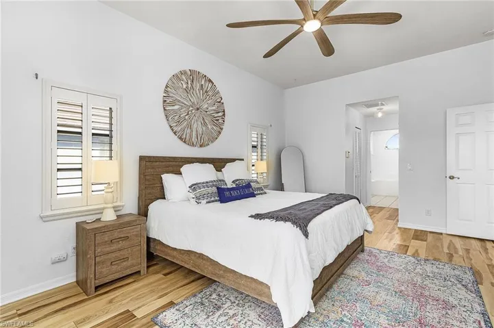 Bedroom featuring light wood-style flooring, a ceiling fan, and connected bathroom