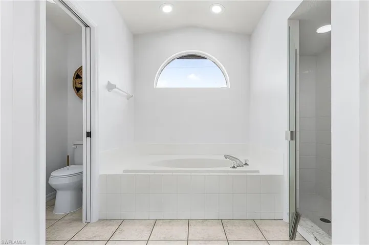 Bathroom with a garden tub, light tile patterned floors, a shower stall, recessed lighting, and vaulted ceiling