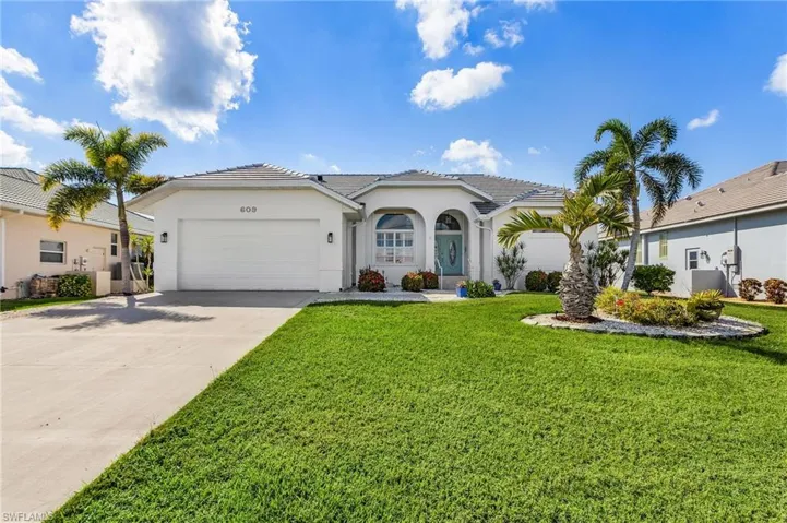 View of front facade with concrete driveway, a tiled roof, stucco siding, a front lawn, and an attached garage