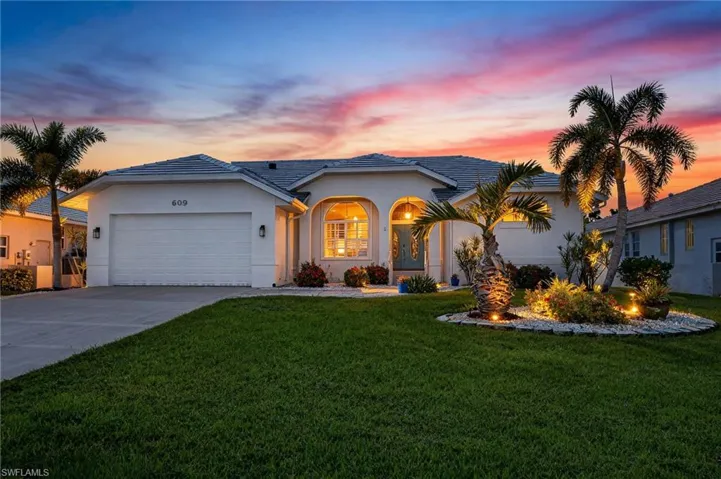 View of front of house with concrete driveway, stucco siding, a front lawn, an attached garage, and a porch