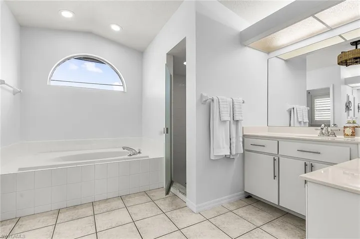 Bathroom with vanity, a garden tub, a stall shower, light tile patterned floors, and recessed lighting