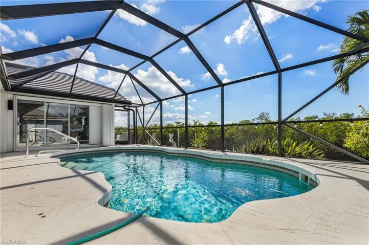 Outdoor pool with a sunroom, glass enclosure, and a patio