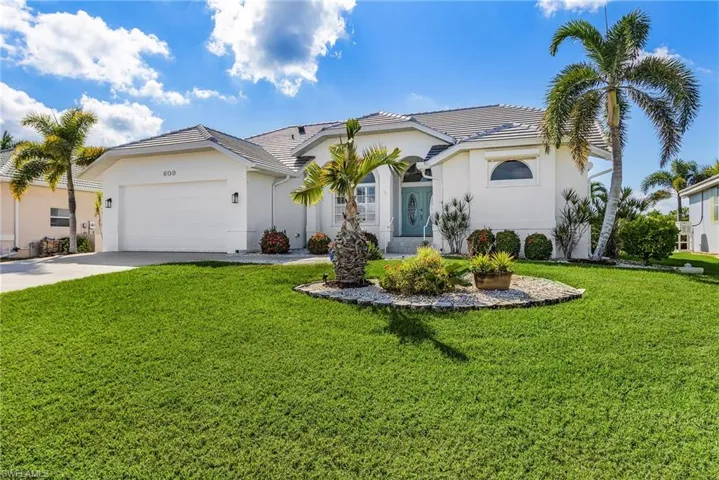 View of front of home with stucco siding, driveway, a front lawn, and an attached garage