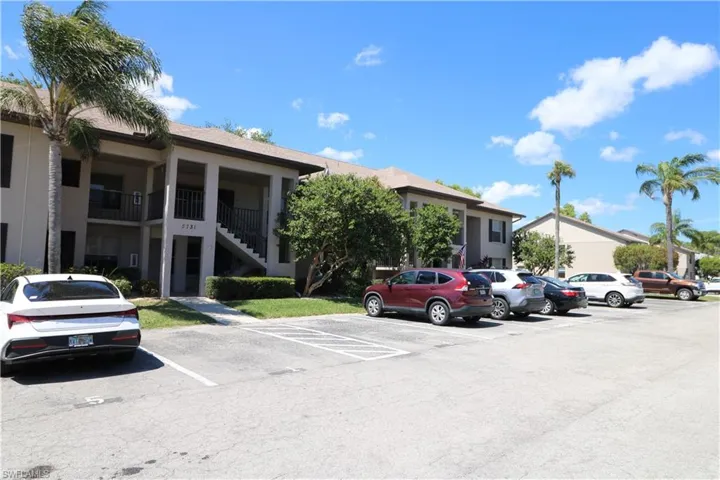 View of building exterior featuring uncovered parking and stairway