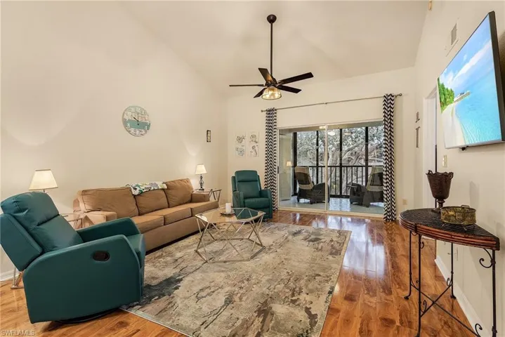 Living room featuring high vaulted ceiling, wood finished floors, and a ceiling fan