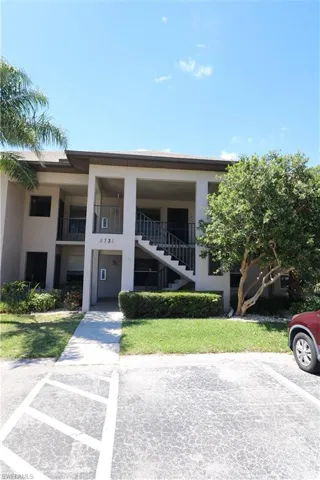 View of property featuring stairs and uncovered parking