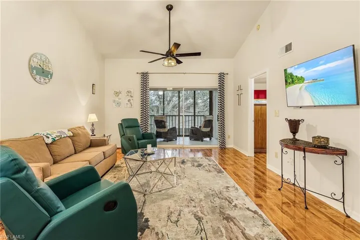 Living room with light wood-type flooring, lofted ceiling, and a ceiling fan