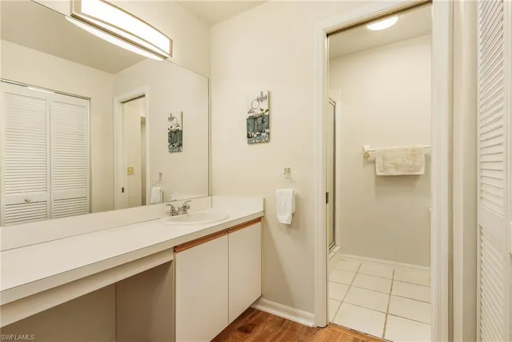 Full bath featuring a closet, vanity, a shower stall, and light wood-type flooring