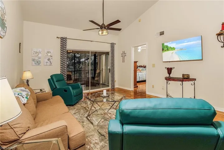 Living room with wood finished floors, high vaulted ceiling, and ceiling fan