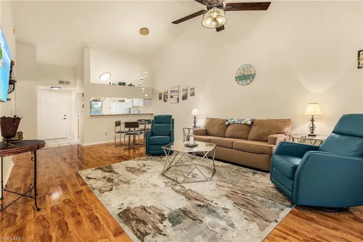 Living area with high vaulted ceiling, light wood-type flooring, and ceiling fan
