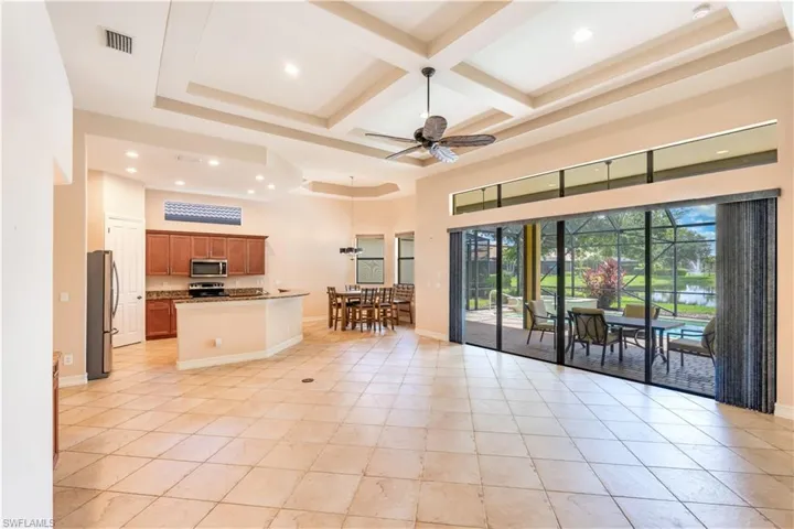 Kitchen featuring appliances with stainless steel finishes, beamed ceiling, coffered ceiling, light tile flooring, and ceiling fan