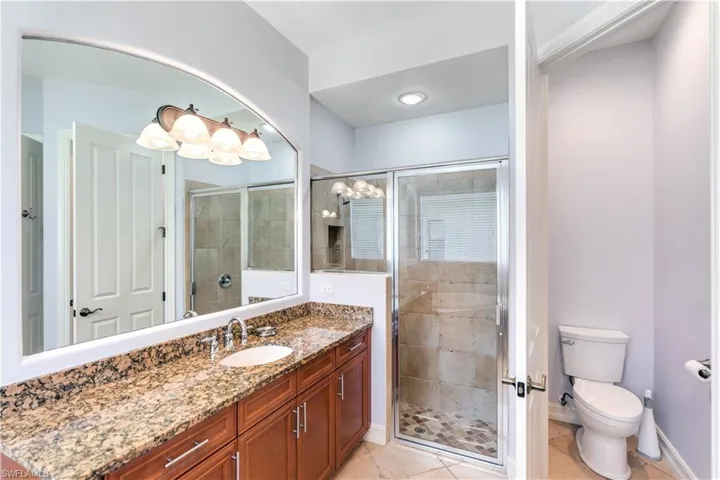 Bathroom featuring a shower with shower door, oversized vanity, toilet, and tile floors