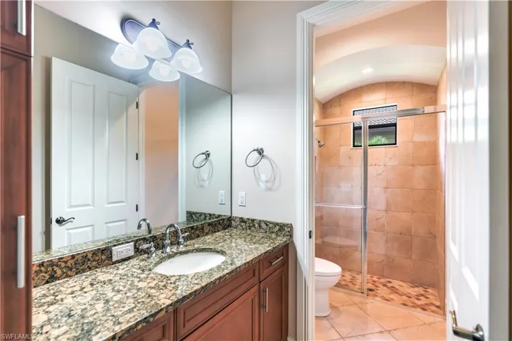 Bathroom featuring tile flooring, walk in shower, vanity, and toilet