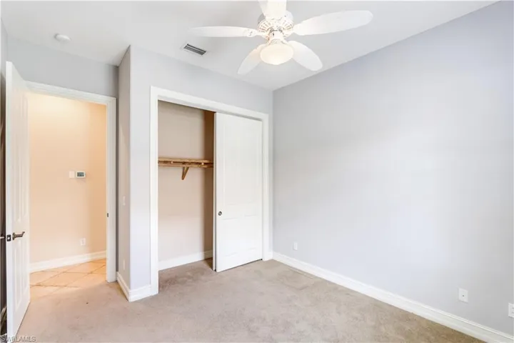 Unfurnished bedroom featuring light colored carpet, a closet, and ceiling fan