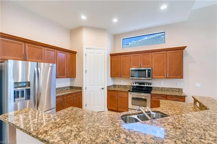Kitchen with stainless steel appliances, sink, and light stone countertops