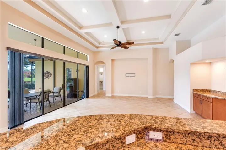 Tiled empty room with beam ceiling, coffered ceiling, and ceiling fan