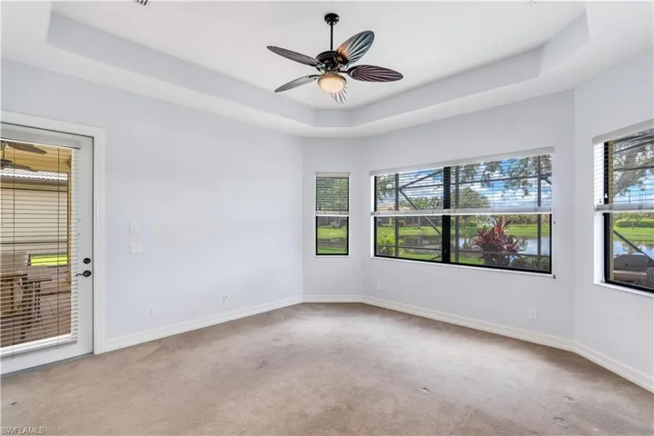 Empty room featuring carpet, ceiling fan, and a tray ceiling
