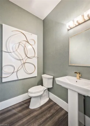 Bathroom with dark wood-style flooring and a textured wall