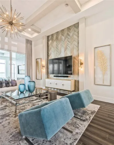 Living area featuring dark wood finished floors, an accent wall, beam ceiling, coffered ceiling, and a chandelier