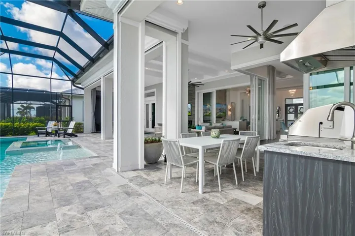 View of patio featuring ceiling fan, glass enclosure, outdoor dining space, a sunroom, and a pool with connected hot tub