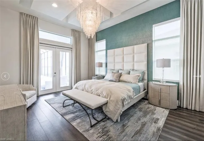 Bedroom featuring french doors, access to exterior, dark wood finished floors, and a chandelier