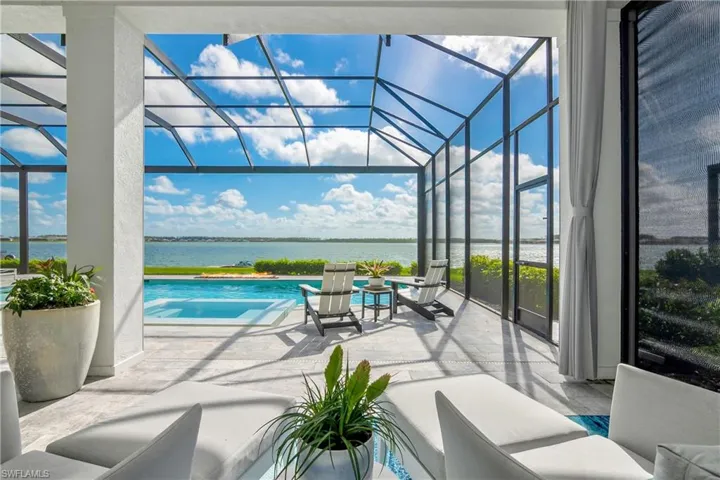 Outdoor pool featuring a sunroom, glass enclosure, a patio area, and a water view