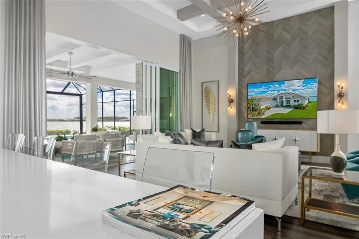 Living area featuring an accent wall, a ceiling fan, coffered ceiling, a towering ceiling, and a chandelier