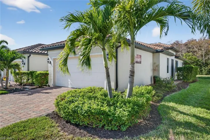 View of home's exterior with an attached garage, stucco siding, a tiled roof, and driveway