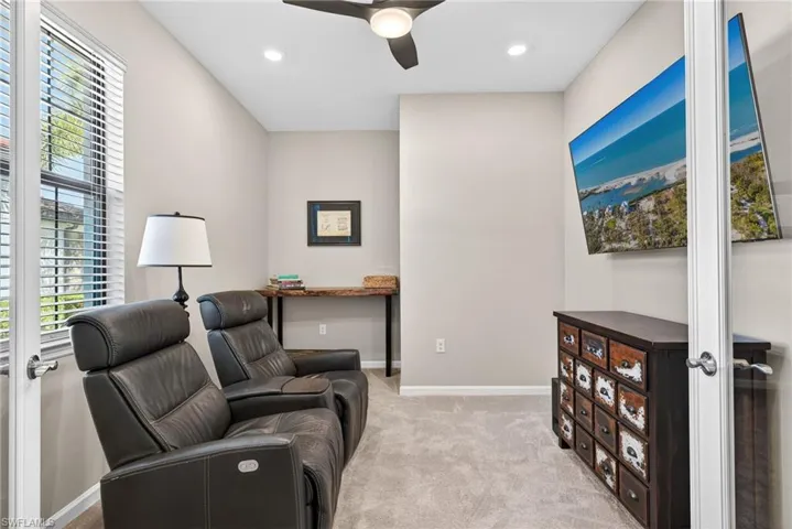 Living area featuring light colored carpet, a ceiling fan, and recessed lighting