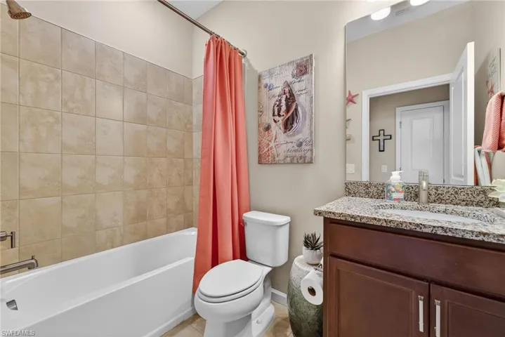 Bathroom with vanity, shower / bath combination with curtain, and light tile patterned floors