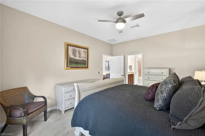 Carpeted bedroom with a ceiling fan and connected bathroom