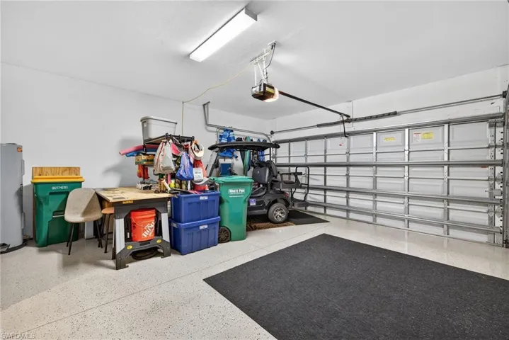 Garage featuring electric water heater and a garage door opener
