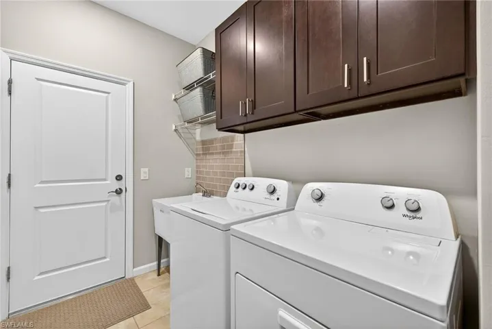 Washroom featuring washer and clothes dryer, light tile patterned floors, and cabinet space
