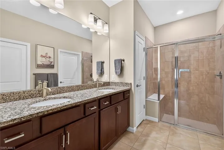 Bathroom featuring double vanity, a shower stall, and light tile patterned floors