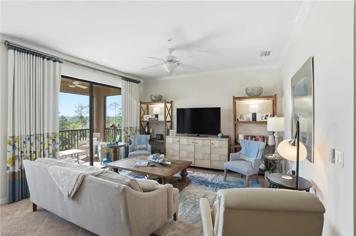 Living area with a ceiling fan, crown molding, and tile patterned flooring