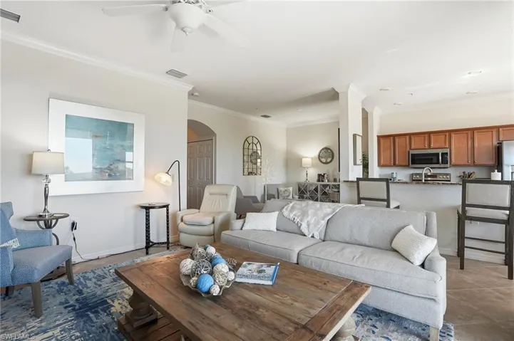Living room with ornamental molding, arched walkways, and a ceiling fan