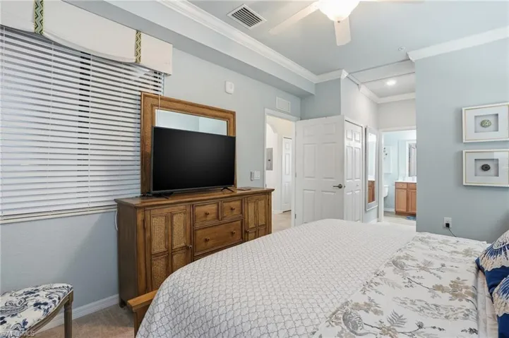 Bedroom featuring crown molding, a closet, light carpet, ceiling fan, and connected bathroom