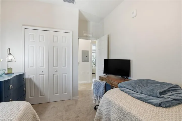 Bedroom featuring light carpet, a closet, and electric panel