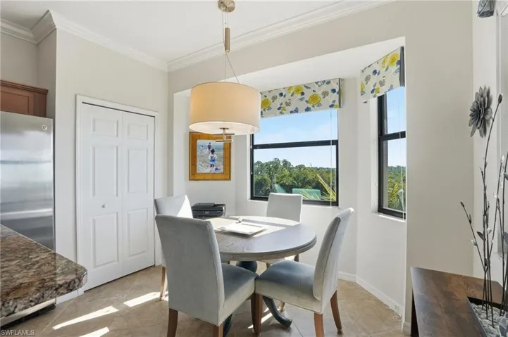 Dining space with crown molding and light tile patterned floors