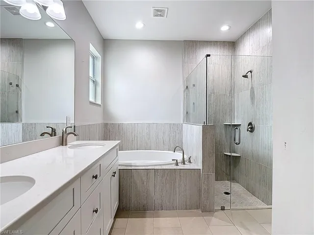 The master bathroom features a double vanity with white countertops, a built-in bathtub, and a tiled shower with a glass enclosure
