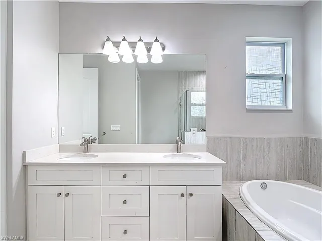 The master bathroom features a double vanity with white cabinetry and light-colored countertops, dual sinks, and a large mirror