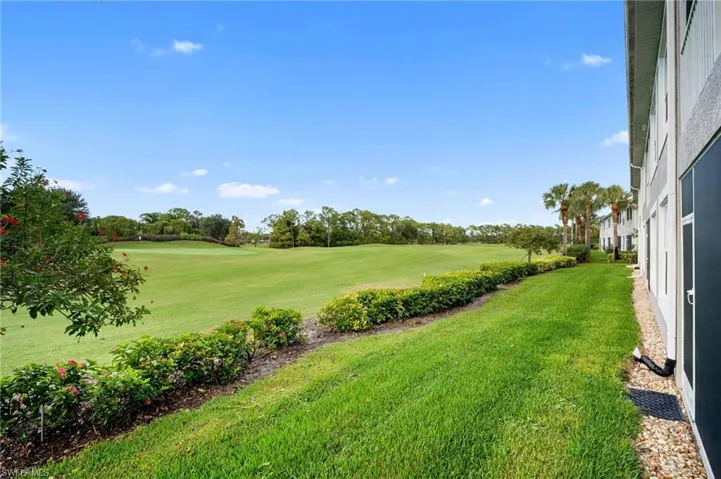 View of green lawn with view of wooded area and view of golf course