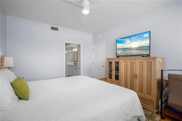 Bedroom featuring ceiling fan, ensuite bath, and light wood finished floors