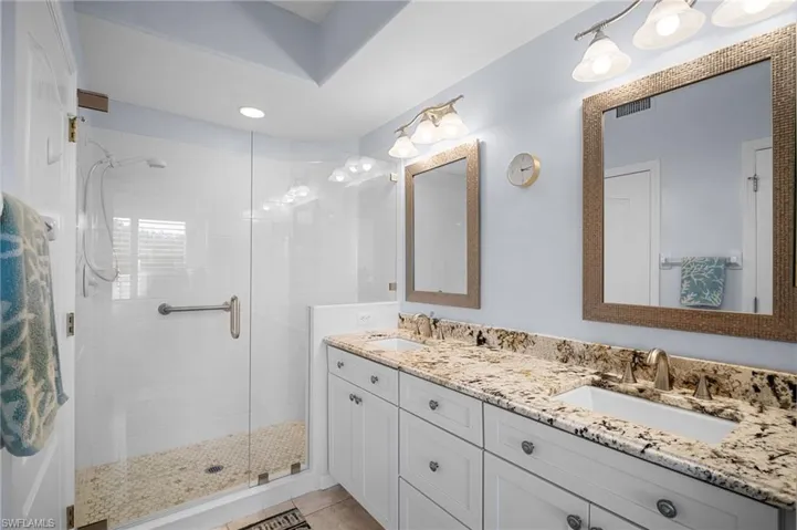 Full bathroom featuring double vanity and a stall shower