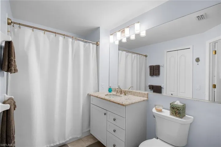 Full bath with vanity, curtained shower, and light tile patterned floors