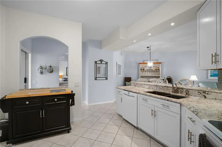 Kitchen with white appliances, recessed lighting, light tile patterned floors, light stone countertops, and white cabinets
