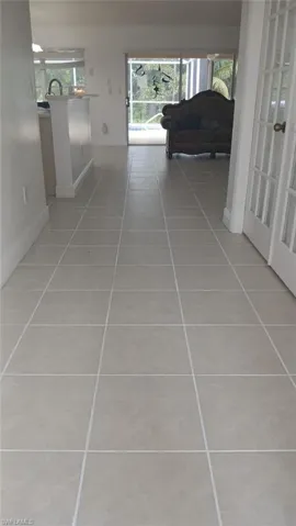 Hallway featuring light tile patterned flooring and healthy amount of natural light