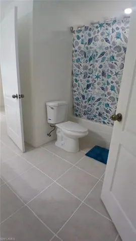 Bathroom with shower / tub combo with curtain and light tile patterned floors