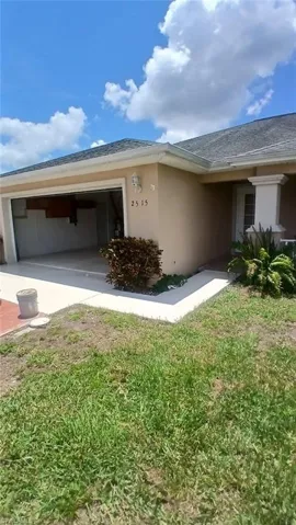 View of side of home featuring stucco siding, an attached garage, and a lawn