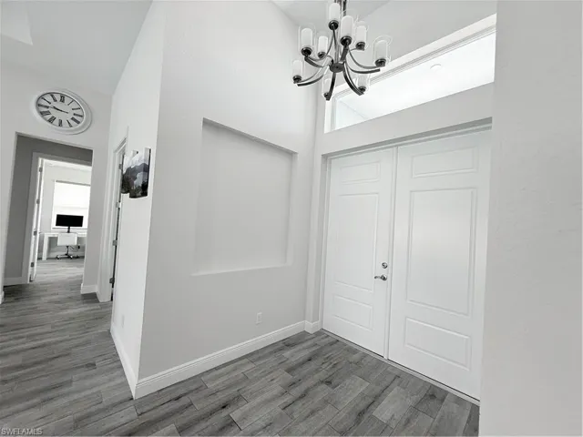 Foyer with a chandelier, wood finished floors, and a towering ceiling